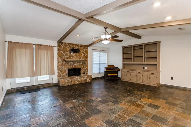 a view of an empty room with fire place and a window