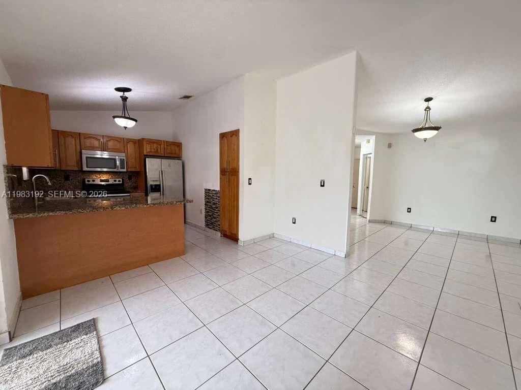 18260 Southwest 142nd Place Miami, FL 33177 - Photo 4 of 30 a kitchen with stainless steel appliances kitchen island granite countertop a refrigerator and a stove top oven