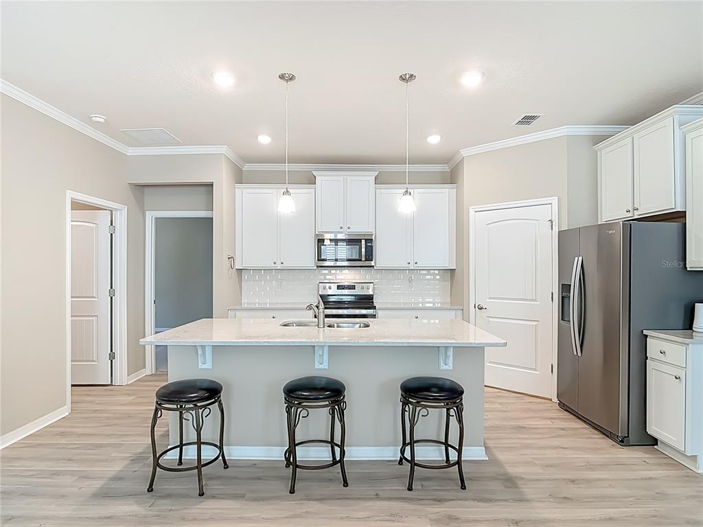 1632 Delphi Way New Smyrna Beach, FL 32168 - Photo 14 of 52 a kitchen with stainless steel appliances a table chairs refrigerator and wooden cabinets