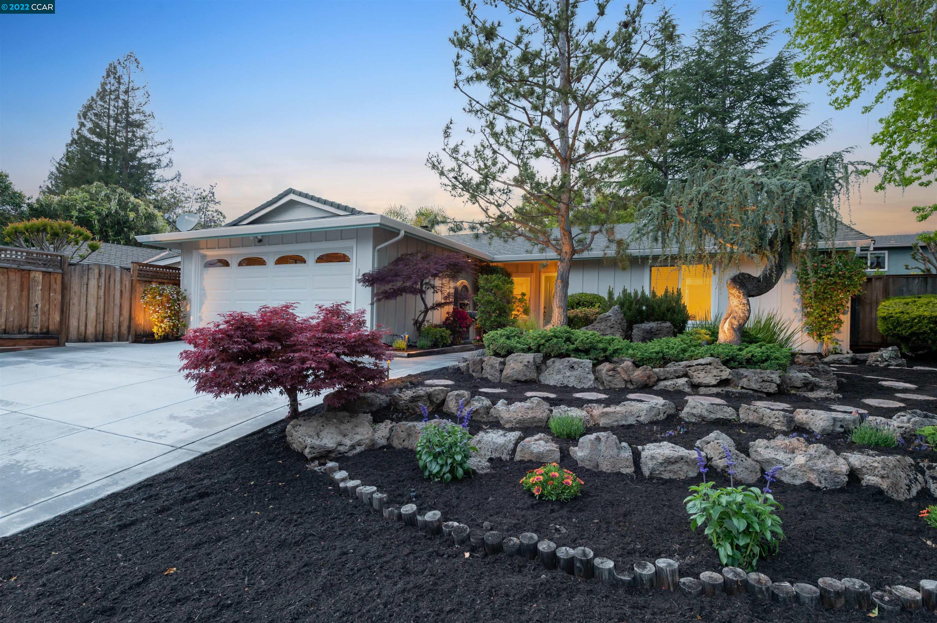 a front view of a house with a yard and a garden
