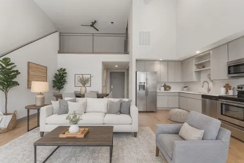 a living room with furniture kitchen view and a potted plant