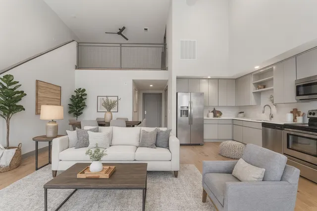 a living room with furniture kitchen view and a potted plant
