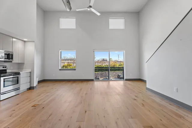 a view of kitchen with stainless steel appliances wooden floor and window
