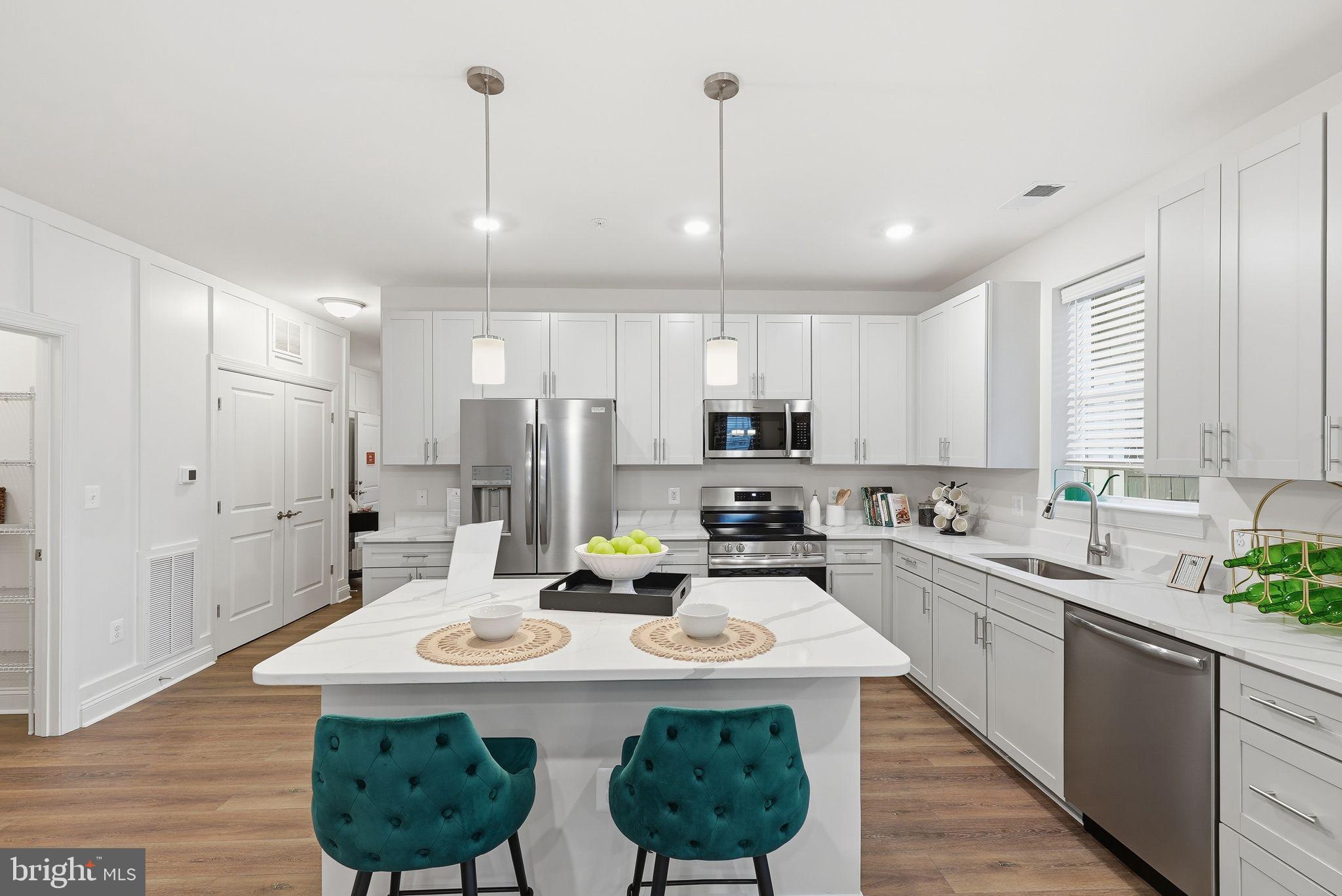 a kitchen with stainless steel appliances kitchen island granite countertop a sink a stove a refrigerator cabinets and a dining table with wooden floor