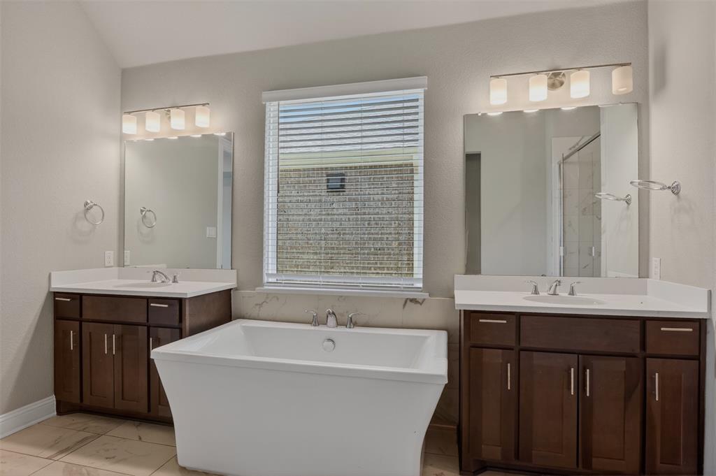 16812 Bitterroot Road Justin, TX 76247 - Photo 21 of 27 a bathroom with a double vanity sink large mirror and bathtub