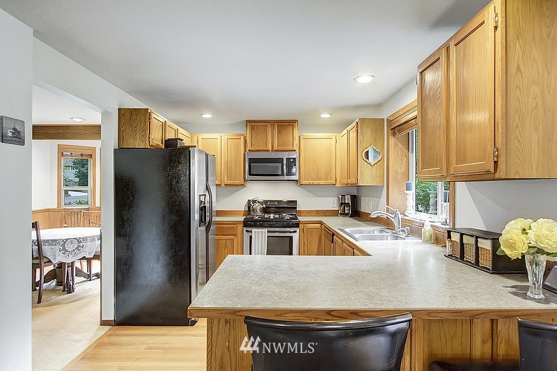 19908 4th Avenue Southeast Bothell, WA 98012 - Photo 4 of 21 a kitchen with stainless steel appliances granite countertop a refrigerator a stove a sink a dining table and chairs with wooden floor