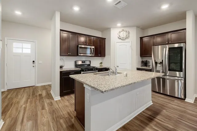 a kitchen with stainless steel appliances granite countertop a lot of counter space and wooden floor