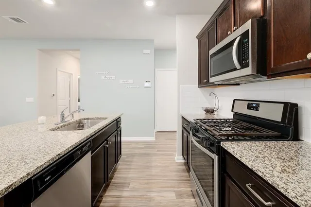 a kitchen with stainless steel appliances granite countertop a stove top oven a sink and dishwasher
