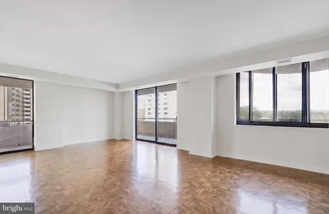 a view of an empty room with a window and wooden floor