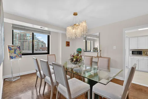 a dining room with furniture a large window and a chandelier