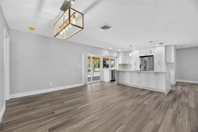 a living room with stainless steel appliances wooden floor and large window
