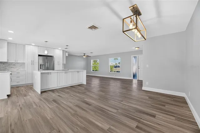 a kitchen with kitchen island granite countertop a refrigerator and a stove top oven