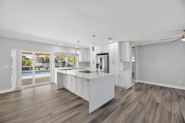 a kitchen with granite countertop a refrigerator a sink and white cabinets