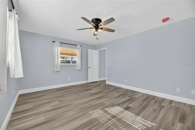 a view of an empty room with wooden floor and a window