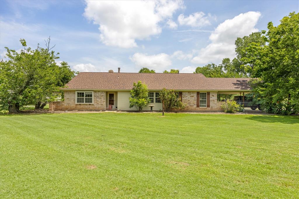 Ranch-style residence featuring a brick facade, covered carport, and a brown shingle roof