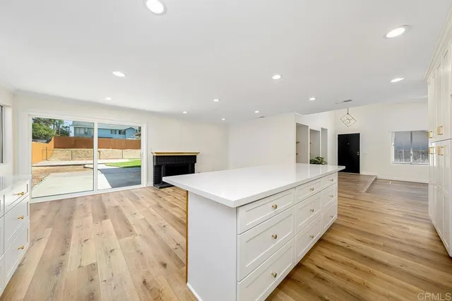 a large white kitchen with wooden floors and fireplace