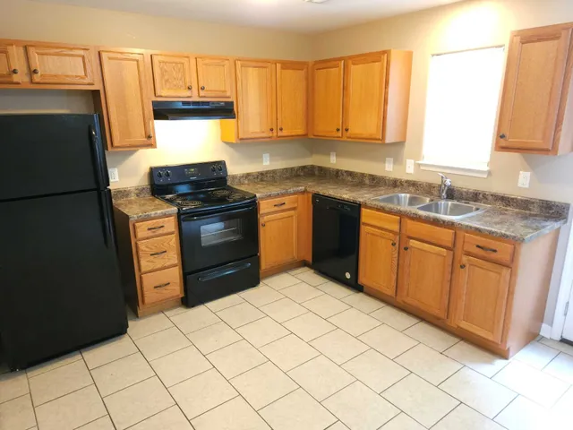 a kitchen with granite countertop a refrigerator sink and cabinets
