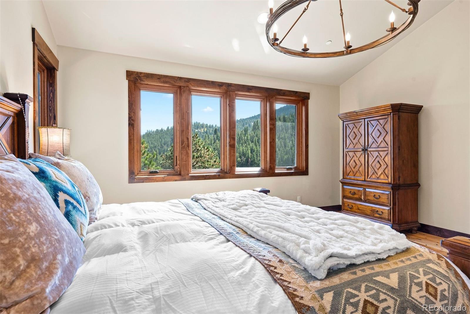 610 Clear Creek Road Evergreen, CO 80439 - Photo 18 of 50 a bedroom with a bed and a chandelier