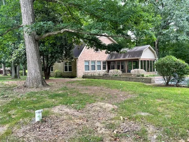 a backyard of a house with large trees and wooden fence