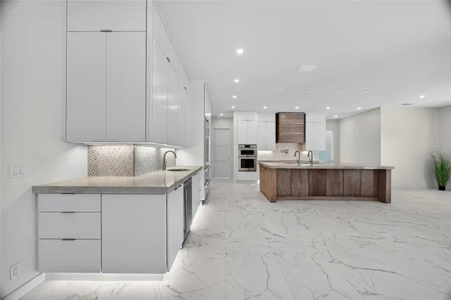 a large white kitchen with a large window and cabinets