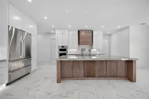 a large kitchen with granite countertop a large counter top stainless steel appliances and cabinets