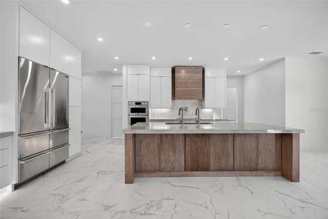 a large kitchen with granite countertop a large counter top stainless steel appliances and cabinets