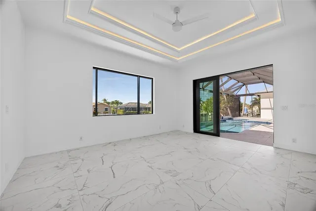 an empty room with floor to ceiling windows and a ceiling fan