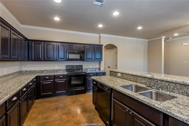 a kitchen with stainless steel appliances granite countertop wooden cabinets a stove a sink and a oven