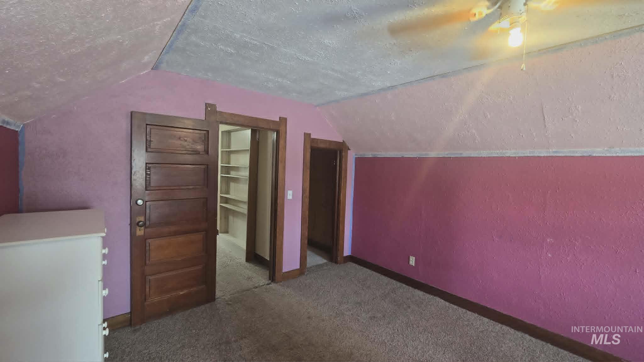 1212 Main Street Pomeroy, WA 99347 - Photo 18 of 18 Sloped ceiling room featuring textured walls, wood-finish panel doors, and a ceiling fan with integrated lighting