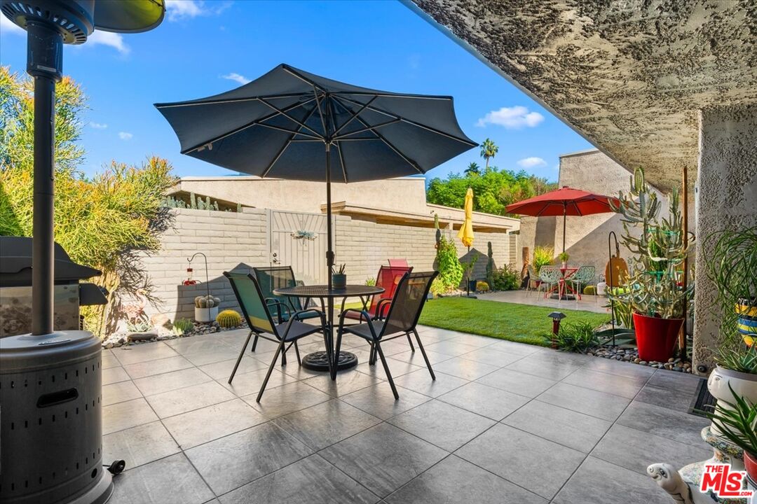 1111 East Ramon Road, Unit 17 Palm Springs, CA 92264 - Photo 17 of 34 a patio with a table and chairs under an umbrella