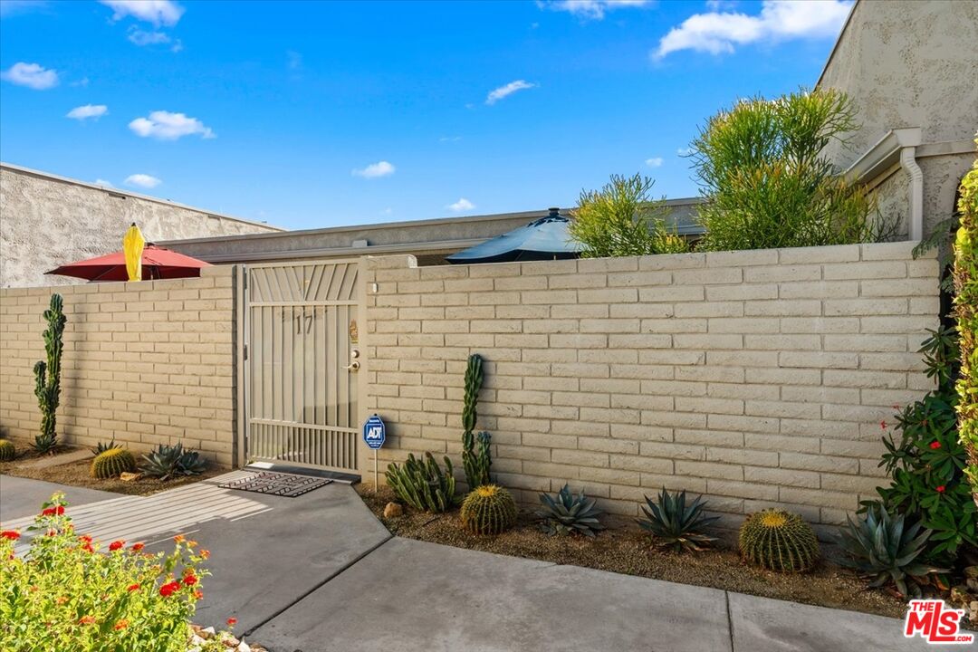 1111 East Ramon Road, Unit 17 Palm Springs, CA 92264 - Photo 23 of 34 a backyard of a house with potted plants and palm tree