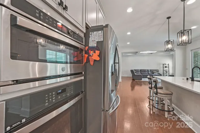 a kitchen with stainless steel appliances granite countertop a refrigerator a stove and a wooden floors