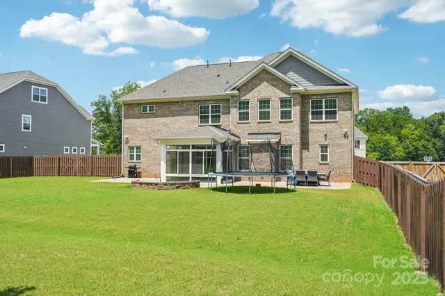 a view of a white house with a yard table and chairs
