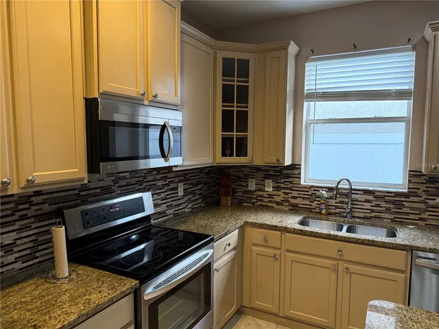 a kitchen with granite countertop a sink a stove and cabinets