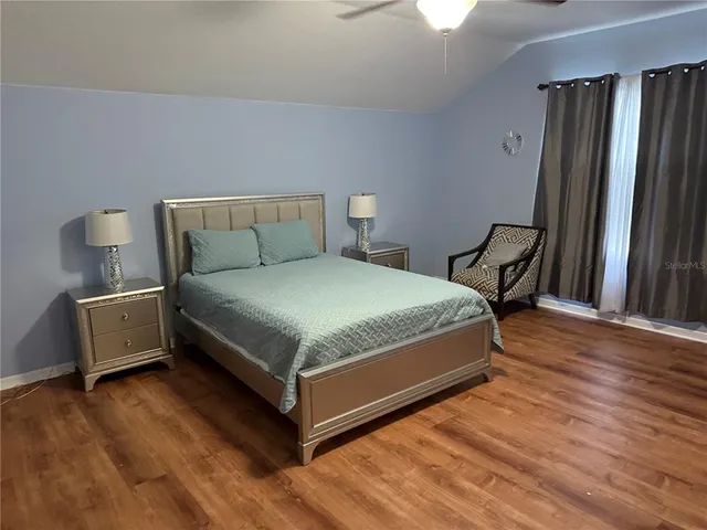 a bedroom with a bed wooden floor and window
