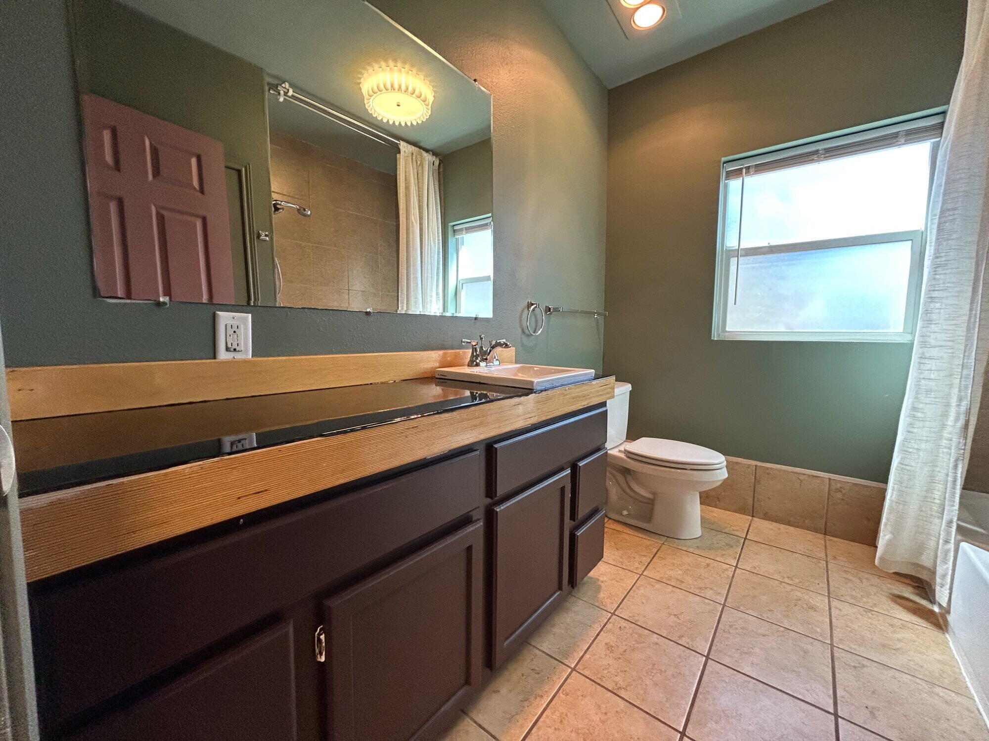3118 37th Street, Unit FRONT Lubbock, TX 79413 - Photo 12 of 16 a bathroom with a sink a toilet and mirror