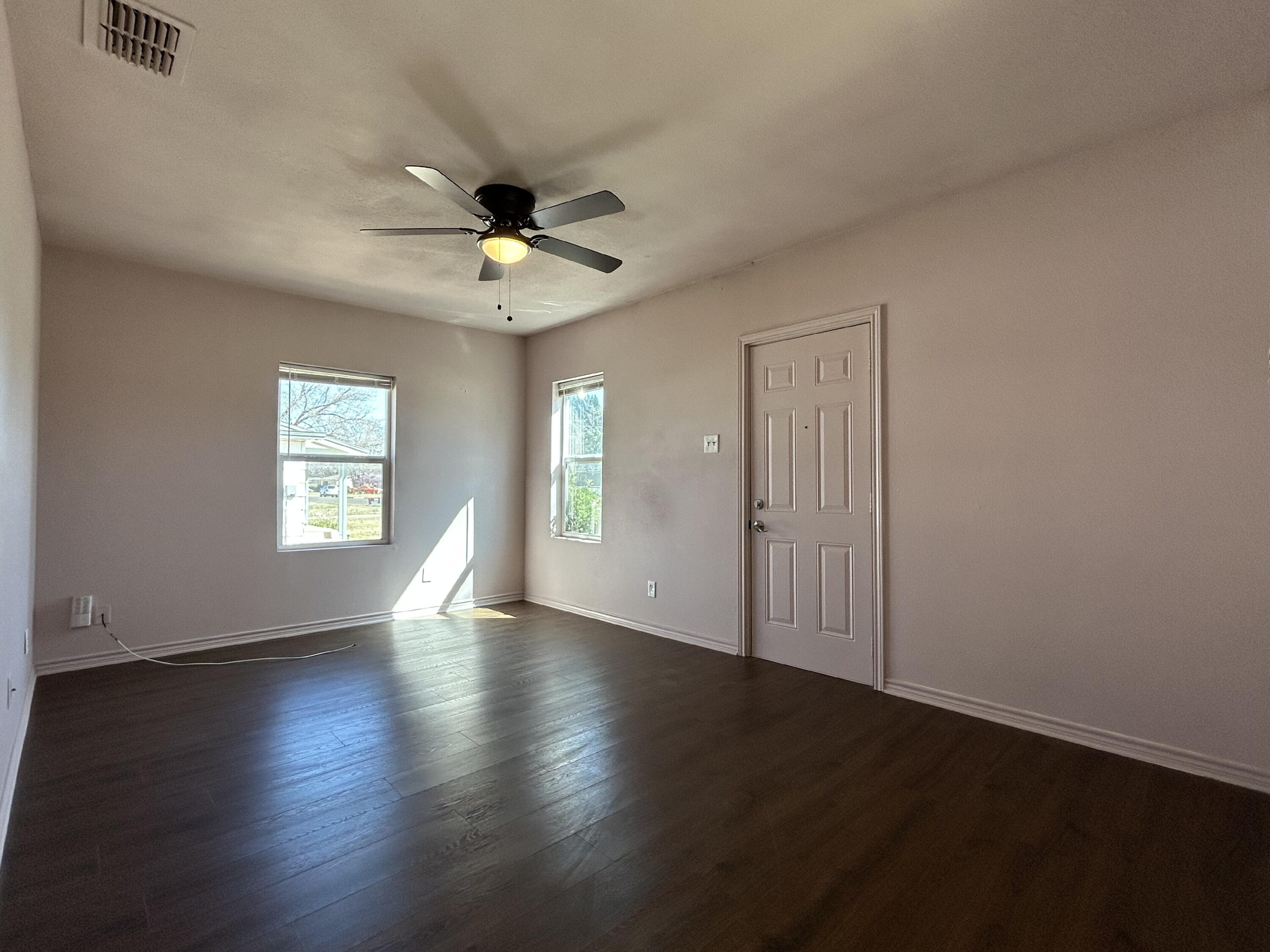 3118 37th Street, Unit FRONT Lubbock, TX 79413 - Photo 2 of 16 a view of an empty room with wooden floor and a window
