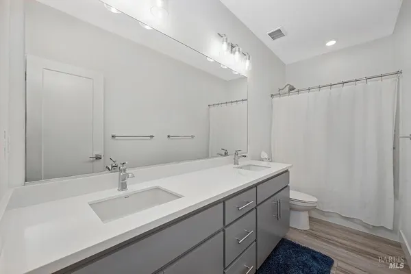 a bathroom with a sink double vanity granite and a toilet