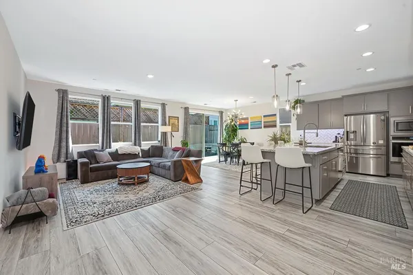 a living room with lots of furniture wooden floor and a large window