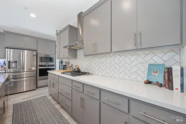 a kitchen with granite countertop white cabinets and stainless steel appliances
