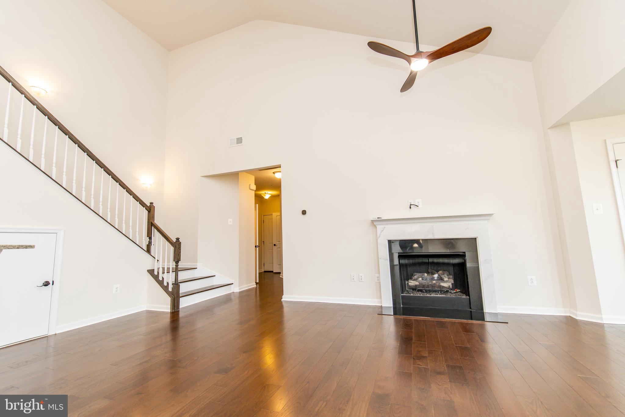 4861 Finnical Way, Unit 401 Frederick, MD 21703 - Photo 12 of 54 a view of an empty room with wooden floor fireplace and a window