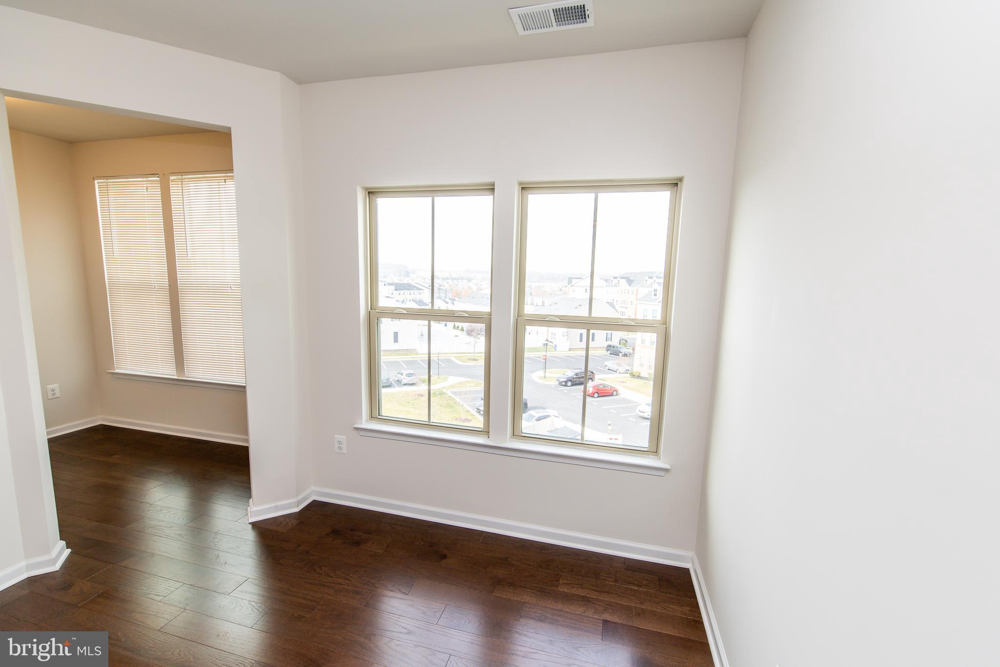 4861 Finnical Way, Unit 401 Frederick, MD 21703 - Photo 17 of 54 an empty room with wooden floor and windows