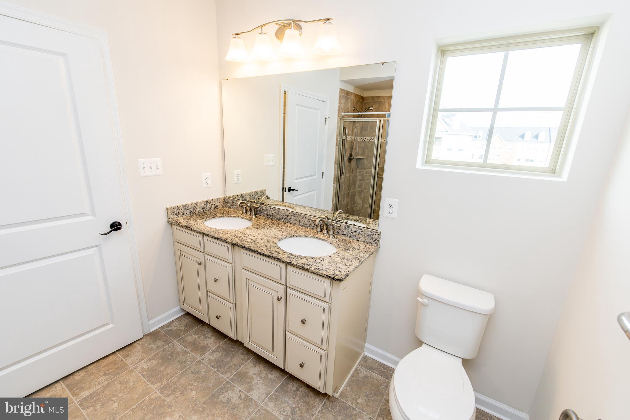 4861 Finnical Way, Unit 401 Frederick, MD 21703 - Photo 36 of 53 a bathroom with a granite countertop toilet sink and mirror