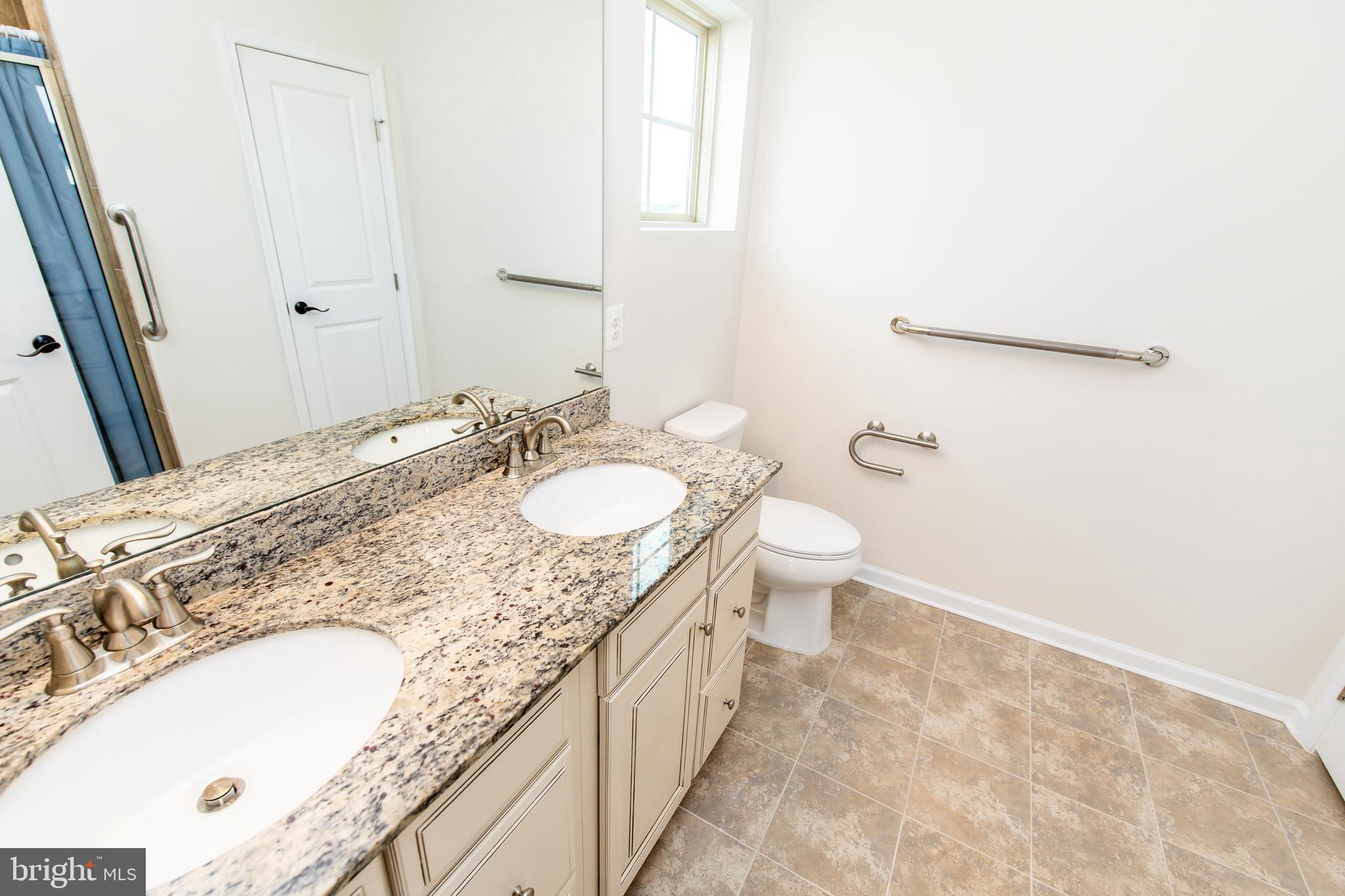 4861 Finnical Way, Unit 401 Frederick, MD 21703 - Photo 38 of 54 a spacious bathroom with a granite countertop sink a toilet and a mirror