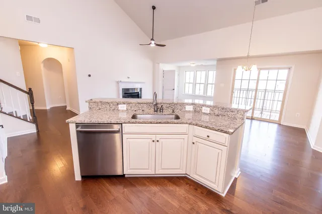 a kitchen with stainless steel appliances granite countertop wooden floors and white cabinets