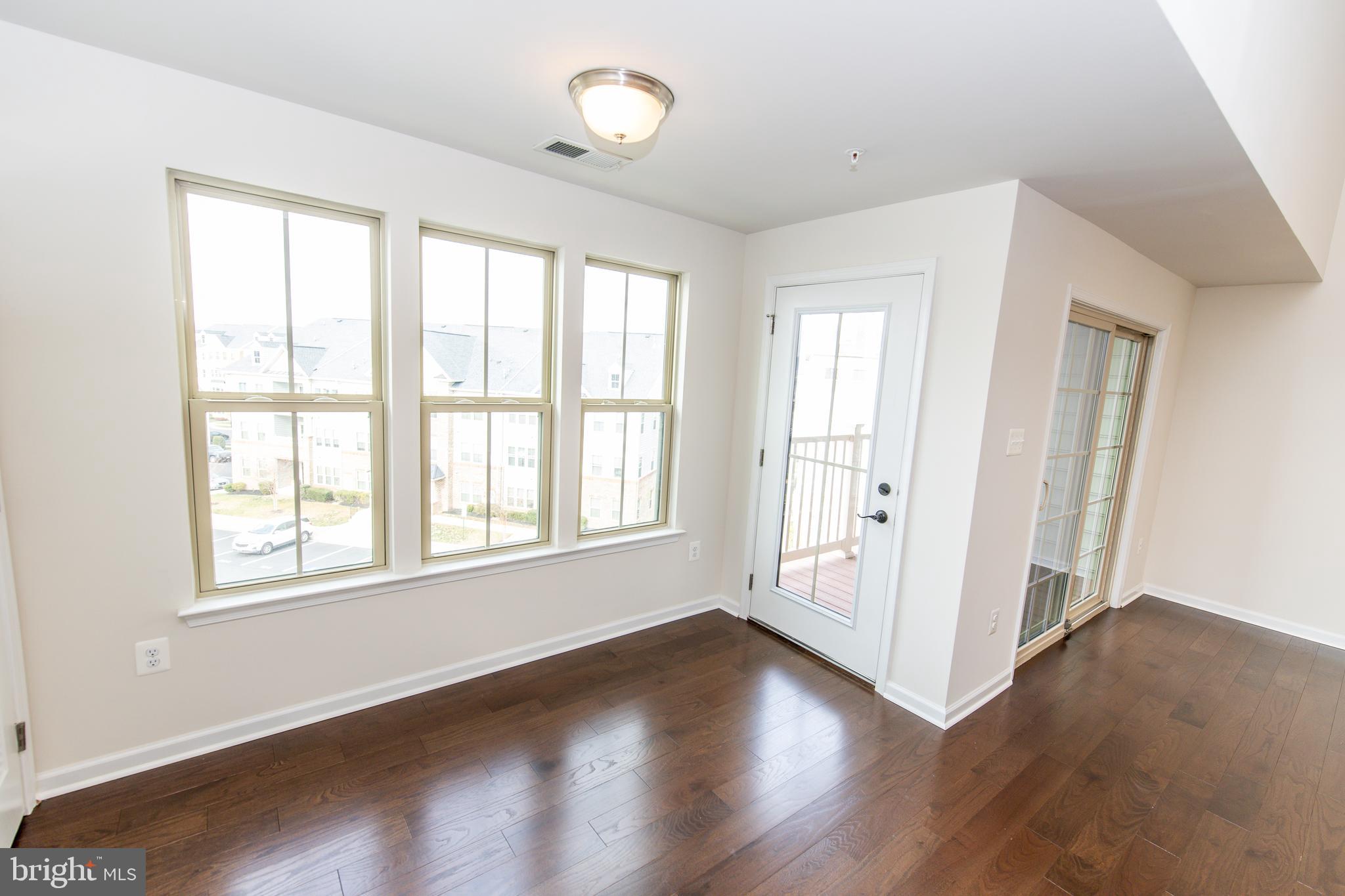 4861 Finnical Way, Unit 401 Frederick, MD 21703 - Photo 9 of 53 an empty room with wooden floor and windows