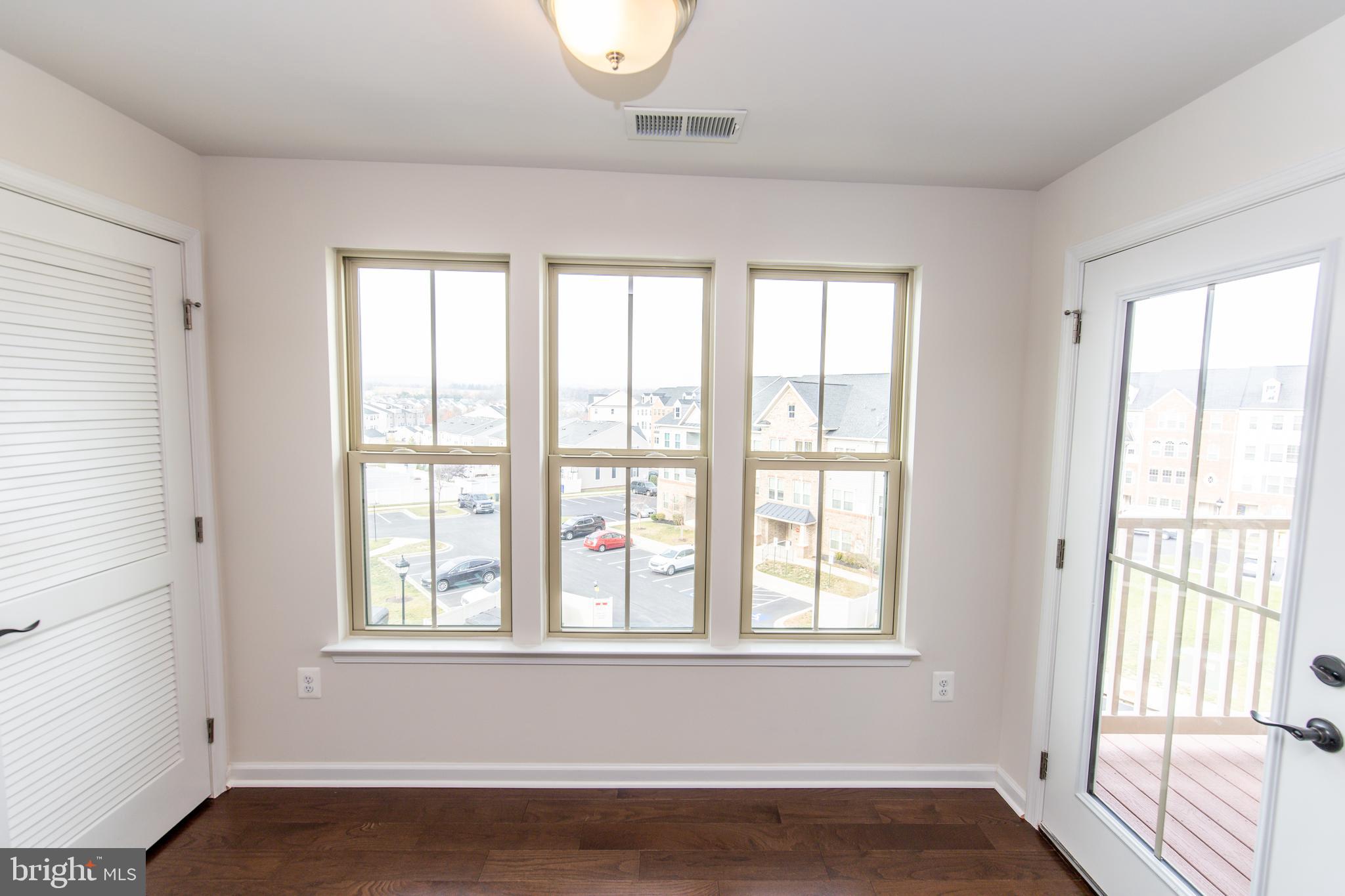 4861 Finnical Way, Unit 401 Frederick, MD 21703 - Photo 10 of 53 a view of an empty room with wooden floor and a window