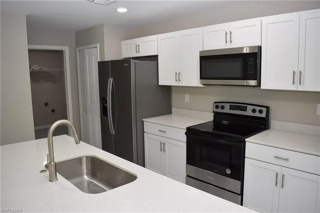 a kitchen with white cabinets a sink and stainless steel appliances