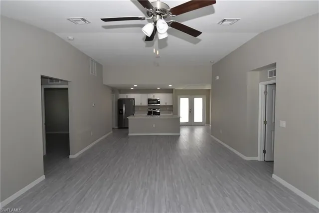 an empty room with wooden floor fan and windows