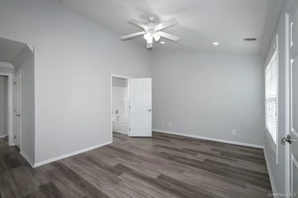a view of an empty room with wooden floor and a ceiling fan